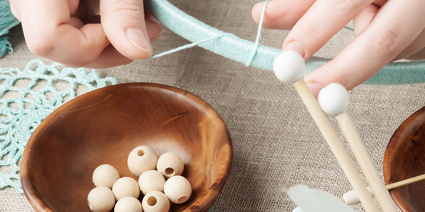 person crafting with wooden beads